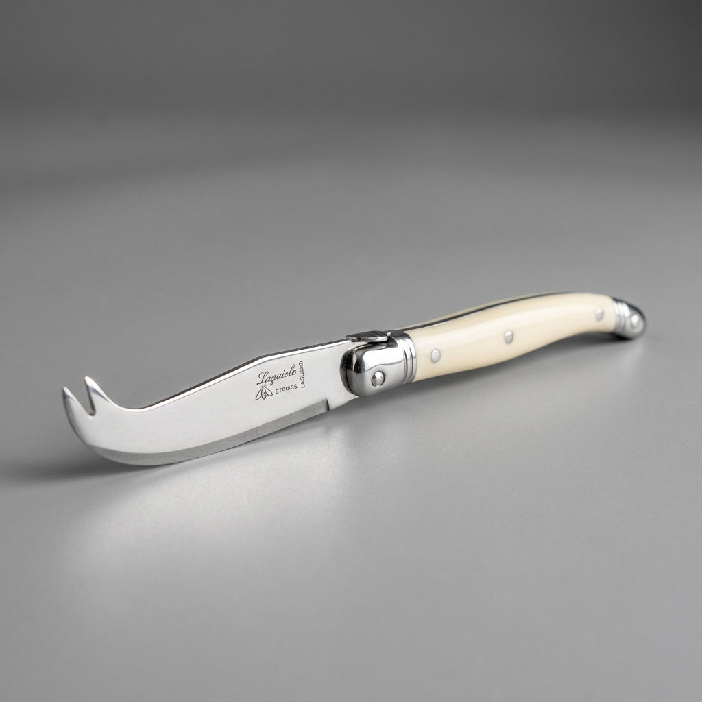 Create a high-resolution, product-focused image of the 'Cheese Knife short - Ivory' set against a sleek, neutral studio backdrop illuminated by softbox lighting, emphasizing the smooth, polished ivory handle and sharp stainless steel blade. Use a shallow d