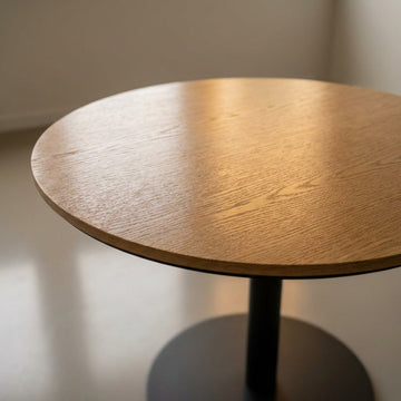 Capture a sophisticated, high-resolution image of a small dining table made from rich oak veneer with a sleek, contemporary design. Use a softbox lighting setup to evenly illuminate the textured wood grain, highlighting its natural warmth and subtle gloss 