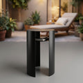 A high-resolution studio shot of the ICO Waipuna Side Table in black, captured from a slightly elevated front-angle perspective using a 50mm lens with a shallow depth of field to emphasize the sleek texture of the powder-coated metal surface. The scene is 