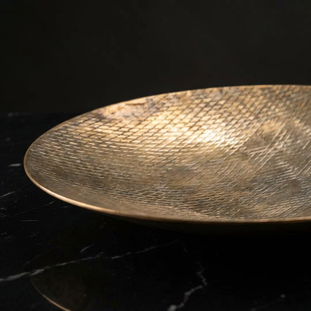 A high-resolution, studio-shot of the Ankara Diamond Plate XL Vintage Brass placed on a sleek black marble surface, illuminated by a softbox lighting setup to highlight the warm, aged brass textures with subtle patina. The camera is positioned at a 45-degr