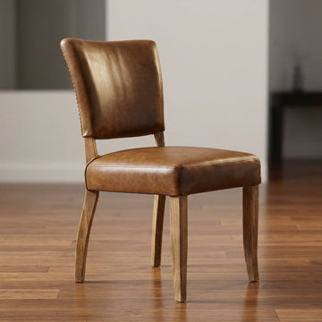 1. Capture a sophisticated, high-resolution studio shot of the Crane Leather Dining Chair in a luxurious setting. Use softbox lighting to create a warm, inviting glow, highlighting the rich, aged brown top-grain semi-aniline leather with subtle reflections