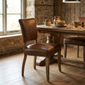 2. Visualize the Crane Leather Dining Chair placed in a cozy, rustic dining room setup, captured with HDR studio lighting to accentuate the textured leather and wood details. Use a slightly lower camera angle, about 30 degrees, with a 35mm lens to bring ou