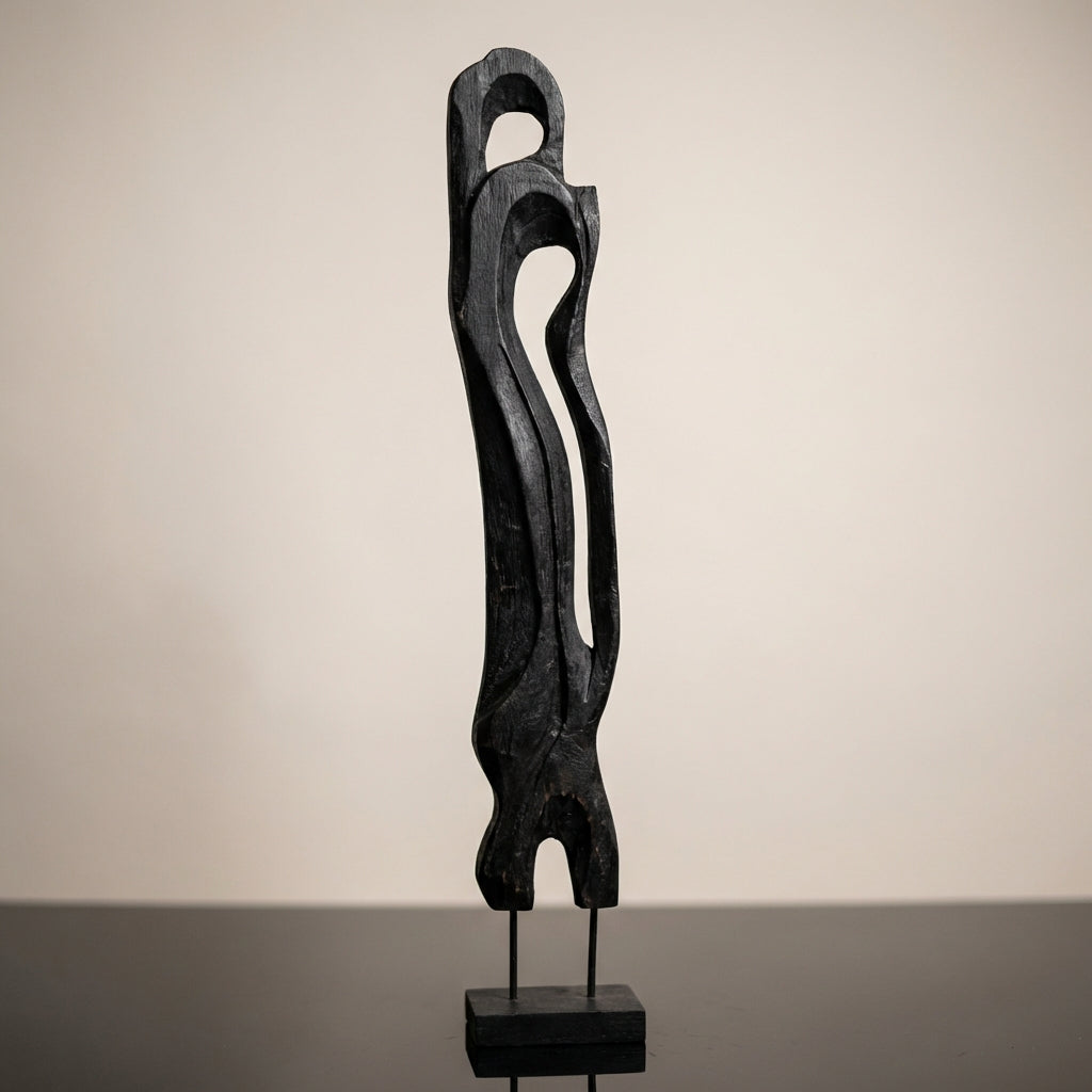 Capture a close-up of the 'Standing Abstract Wooden Art - Black' against a minimalist studio backdrop. Use a softbox lighting setup to highlight the rich textures and matte finish of the black wood, emphasizing the intricate handcrafted carvings. Set the c