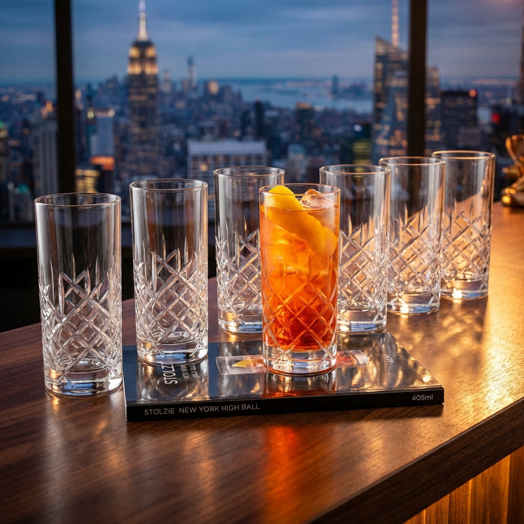 A sleek, high-resolution studio shot of the Stolzie New York High Ball 405ml glass arranged neatly in a custom-designed black velvet-lined box of six. The scene is illuminated with softbox lighting to emphasize the glass's clarity, smooth curves, and subtl