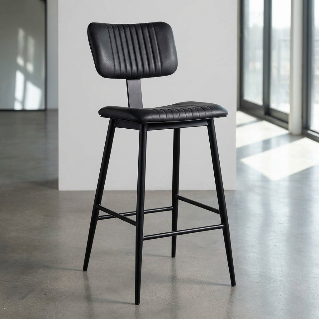 Present the Aviator Bar Stool in a minimalist, well-lit showroom environment using HDR studio lighting to bring out the rich texture of the black powder coating and the durable construction. The shot is a slightly elevated, close-up profile with a 35mm len