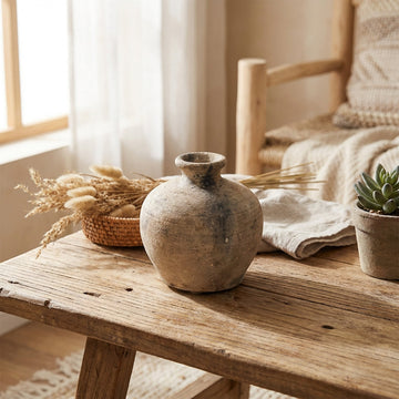 A lifestyle setting featuring a rustic mini pot placed on a weathered wooden table, lit by diffuse daylight streaming through a nearby window, creating gentle shadows and a cozy atmosphere. The shot is taken with a 35mm lens slightly above and at an angle,