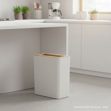 Set indoors in a bright, Scandinavian-inspired modern kitchen scene, featuring the Yamazaki Rubbish Bin Square placed beside a sleek, white countertop. Use HDR studio lighting to evenly illuminate the entire product, capturing its pristine white color and 