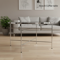 Capture a sophisticated, high-resolution image of the Ibiza B Coffee Table in a modern, stylish living room setting. Use a softbox lighting setup to create soft, even illumination that highlights the sleek chrome frame and the tempered glass top’s reflecti