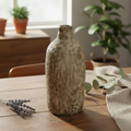 Create a styled lifestyle scene featuring the Earthenware Bottle vessel placed on a vintage wooden countertop in a cozy, sunlight-filled living space. Use HDR studio lighting to evenly illuminate the object, emphasizing its handcrafted, slightly irregular 
