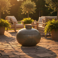 Imagine a warm, inviting lifestyle scene showcasing the Toulouse Iron Pot as a centerpiece in an outdoor patio setting during golden hour. Use HDR outdoor lighting to accentuate the rustic patina and aged character of the iron, with a slight rim light to d