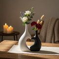 Capture an artistic lifestyle scene featuring the 'Love Vase' placed on a rustic wooden table in a cozy, well-lit living space. Use natural HDR studio lighting to enhance the contrast between the black and white halves of the vase, casting soft shadows tha