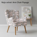 Capture a high-resolution, studio shot of the Noja velvet Arm Chair Pupuga in a modern, minimalist living room setting. Use softbox lighting to highlight the plush velvet upholstery, emphasizing its rich, deep color and luxurious texture. The camera is pos