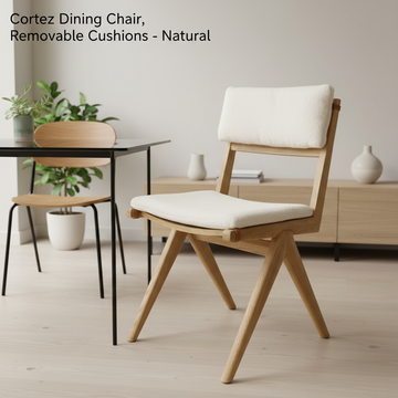 A sleek, contemporary dining room scene featuring the Cortez Dining Chair prominently positioned at a modern glass table. The chair, with its natural timber finish and removable cushions made from recycled plastic bottles, is illuminated with softbox light