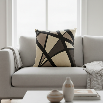 A cinematic studio shot of the 'Cushion Prints - Geometric' placed elegantly on a modern sofa in a brightly lit, minimalist living room. The cushion features a bold, abstract geometric pattern in vibrant colors, with a soft-focus depth of field highlightin