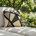 A high-resolution lifestyle setting depicting the 'Cushion Prints - Geometric' atop a chic outdoor lounge in a sunlit garden. The cushion's vivid, angular geometric pattern contrasts beautifully with the natural surroundings, capturing a relaxed, inviting 