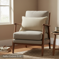 Create a stylized, lifestyle shot of the Dolice Cushion Ecru placed on a rustic, vintage-inspired armchair in a sunlit room. Use diffused daylight to soften the scene, emphasizing the cushion’s handwoven texture and slightly washed-out stonewash look. Posi