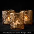 Create a highly detailed product image of the Amber Pearlescent Circles Tea Light Holders set against a sophisticated, dark velvet background to enhance their iridescent glow. Use a softbox lighting setup at a 45-degree angle to softly illuminate the textu