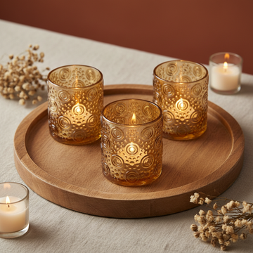Create a luxurious lifestyle scene featuring the Amber Pearlescent Circles Tea Light Holders arranged elegantly on a rustic wooden tray atop a soft, neutral tablecloth, illuminated by HDR studio lighting for balanced, vivid illumination. Use an overhead sh